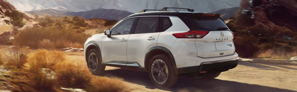 White SUV driving on a dusty mountain trail.