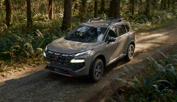 Gray Nissan Rogue Rock Creek driving on a forest trail, showcasing its rugged styling and off-road-ready design.
